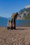 Man on the river assembling a beach lt kayak and taking it out on the water to paddle.