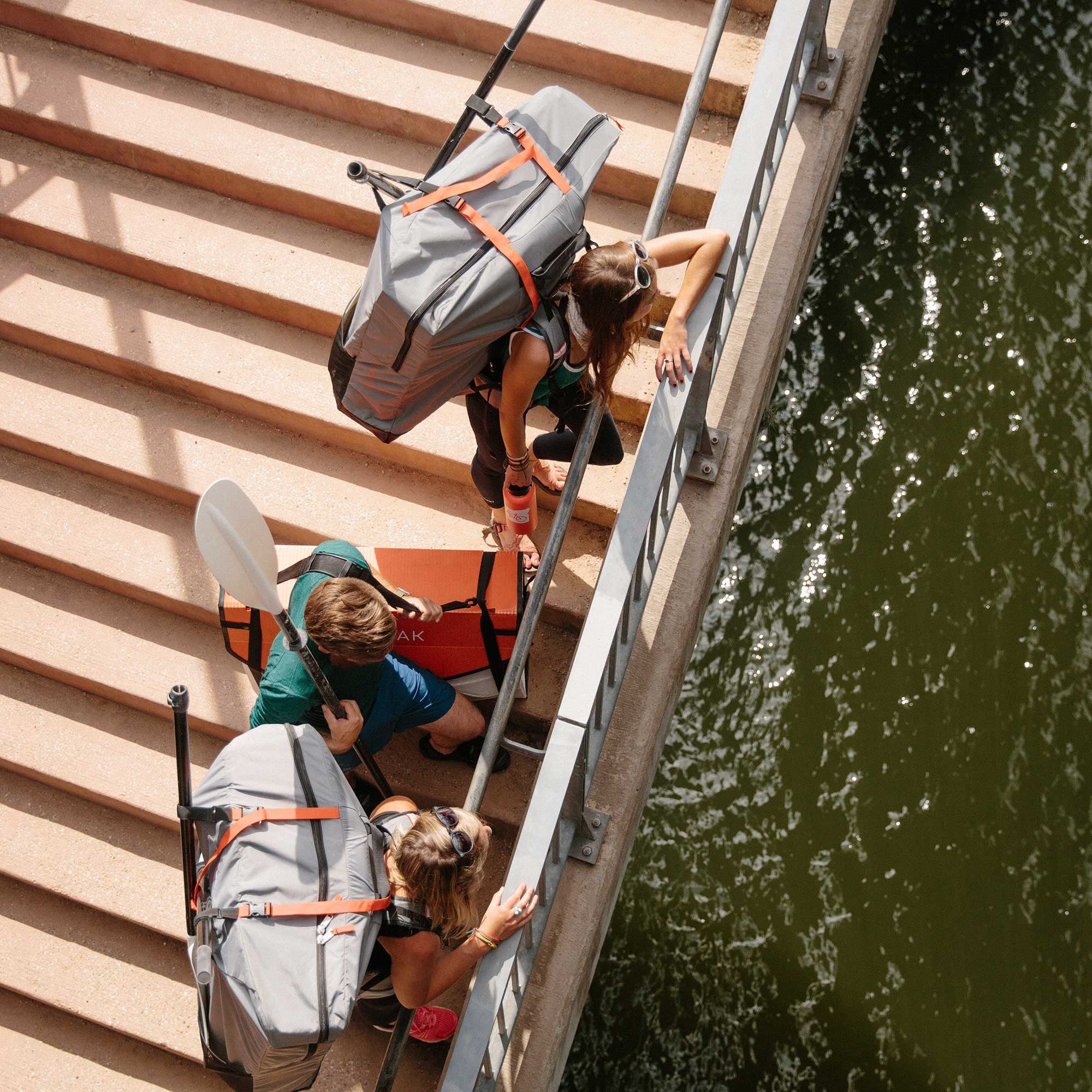 people overseeing the river and carrying their bay st kayaks inside their carrying packs with paddles